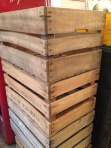 Une pile de caisses en bois rétro avec diverses inscriptions et textes est placée à l'intérieur sur un arrière-plan flou, dégageant un charme brocante.