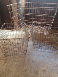 Trois paniers métalliques vides placés sur un sol en béton dégagent un charmant style brocante.