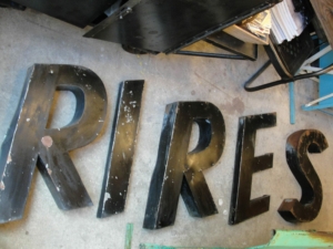Lettres noires épelant "RIRES" posées sur le sol avec divers objets vintage autour d'elles.