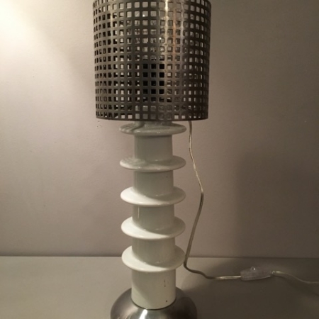La Lampe Isolateur Carouche VENDU est dotée d'un abat-jour cylindrique en métal perforé et d'une base en céramique blanche à plusieurs niveaux sur un support métallique, ce qui la rend parfaite pour ajouter une touche de charme brocante à votre espace. Brocante 93