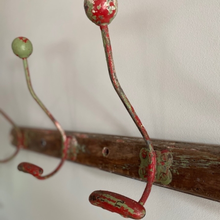 Le Porte-Manteaux 1950 VENDU, doté de deux patères vintage avec peinture écaillée rouge et verte patinée par les intempéries, est monté sur une planche de bois qui dégage une charmante ambiance rétro brocante. Brocante 93