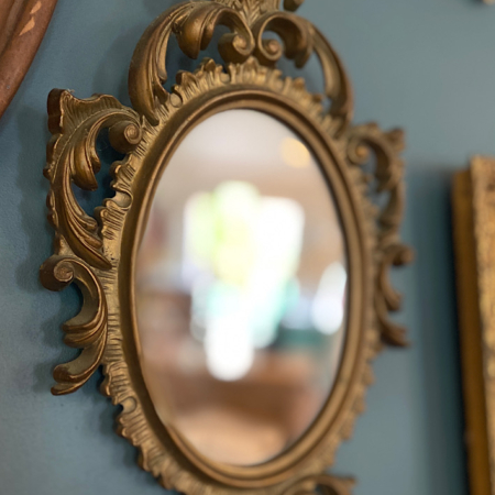 Miroir Rococo 1960 VENDU avec un cadre décoratif doré, dégageant un charme vintage, monté sur un mur de couleur bleu sarcelle. Brocante 93