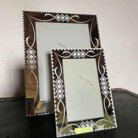 Deux cadres photo décoratifs Cadre Miroir 1960 PM vides, présentant des motifs vintage complexes, sont exposés sur une surface en bois foncé sur un fond uni. Brocante 93