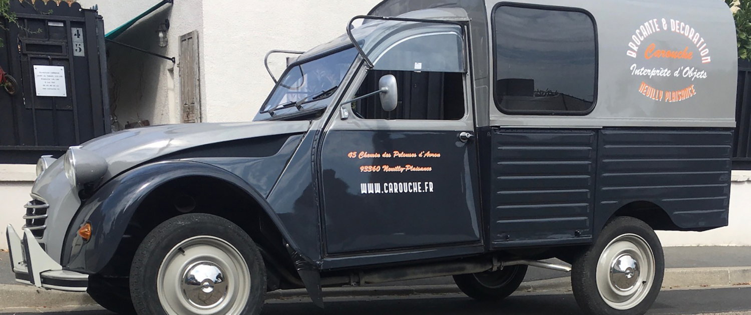 Une camionnette de livraison grise vintage avec signalétique "Brocante et Décoration - Carouche", connue pour son accueil chaleureux, garée dans une charmante rue. Une camionnette de livraison grise vintage avec signalétique "Brocante et Décoration - Carouche", connue pour son accueil chaleureux, garée dans une charmante rue.