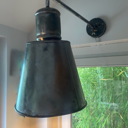 Une applique Applique Industrielle 1960 en noir est suspendue à côté d'une fenêtre, avec des bambous verts visibles à l'extérieur. Brocante 93