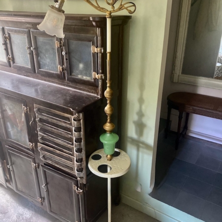 Un lampadaire américain 1930 aux détails complexes se dresse à côté d'une armoire ancienne dans une pièce aux murs verts et au sol recouvert de moquette, dégageant un charme rétro. Brocante 93