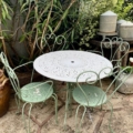 Salon de jardin en fer forgé 1960, en métal vert pâle, idéal pour créer un espace plein de charme dans un jardin verdoyant avec des pots rustiques à proximité. Brocante 93