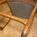 Chaise Baumann modèle Traineau 1960 : chaise en bois dotée d'un dossier gris rembourré, présentée sur un plancher en bois et photographiée de dessus en biais. Brocante 93