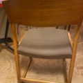 Une chaise Baumann modèle Traineau 1960 avec un siège rembourré marron est vue de derrière, reposant sur un plancher en bois. Brocante 93