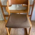 Une chaise Baumann Traineau 1960 avec un dossier en bois courbé et une assise rembourrée marron repose élégamment sur un plancher en bois. Brocante 93