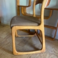 Chaise Baumann Traineau 1960 en bois avec dossier incurvé et assise rembourrée marron, posée sur un plancher en bois. Brocante 93