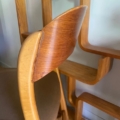 Une chaise Baumann Traineau 1960 en bois avec un dossier incurvé se trouve à côté d'une étagère géométrique en bois. Brocante 93