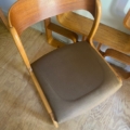 Chaise Baumann Traineau 1960 à dossier incurvé et assise rembourrée marron, exposée sur un plancher en bois. Brocante 93