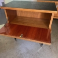Une paire de tables de nuit en bois des années 1950 avec des portes à panneau avant ouvertes, chacune révélant un compartiment de rangement vide, idéales comme tables de chevet vintage. Brocante 93