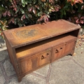 Le Meuble industriel métal riveté, doté de deux portes et d'une étagère ouverte, se trouve à l'extérieur sur un patio en pierre entouré de buissons feuillus. Brocante 93