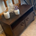 Meuble industriel en métal riveté avec deux vases de fleurs séchées sur le dessus, posé sur un plancher en bois. Brocante 93