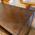 Le Meuble industriel métal riveté présente une base en bois foncé et un plateau en métal riveté, placé à côté de meubles en bois courbé clair pour ajouter une touche industrielle à l'espace. Brocante 93