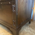 Gros plan du coin du meuble industriel métal riveté, montrant ses charnières et rivets métalliques rivetés sur un plancher en bois. Brocante 93