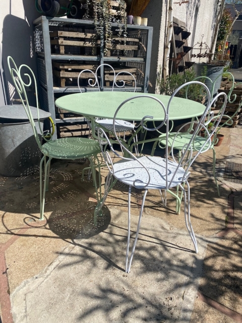 Le Salon de jardin en fer forgé 1950, avec sa table en métal vert pâle et ses quatre chaises ornées, apporte une charmante ambiance vintage à toute terrasse ensoleillée. Brocante 93