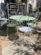 Le Salon de jardin en fer forgé 1950, avec sa table en métal vert pâle et ses quatre chaises ornées, apporte une charmante ambiance vintage à toute terrasse ensoleillée. Brocante 93