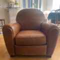 Paire de fauteuils Club 1940 en cuir marron présentée dans un salon ensoleillé avec parquet et mobilier élégant en arrière-plan. Brocante 93