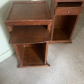 Deux tables de nuit en bois, l'une avec une étagère coulissante et les deux avec des compartiments de rangement ouverts, sur un sol en béton. Brocante 93