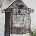 La Cage déco jard est une grande cage à oiseaux vide en fil de fer qui est suspendue à l'extérieur près d'un mur et de plantes vertes - une inspiration parfaite pour la décoration jardin. Brocante 93