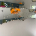 Gros plan sur le Miroir biseauté 1950 aux bords festonnés, reflétant des lampes suspendues colorées et une partie d'un mur, mettant en valeur l'élégance intemporelle de ce miroir vintage. Brocante 93