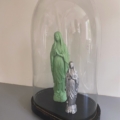 Le Globe de mariage 1950 présente deux statues de la Vierge Marie, l'une verte, l'autre argentée, joliment présentées sous un dôme de verre sur un socle noir, pour un charme vintage. Brocante 93
