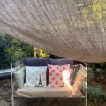 Le Lit en fer forgé 1950 ajoute un charme classique à votre jardin, placé sous un auvent ombragé et agrémenté de coussins à pois et de coussins Tour Eiffel pour une retraite en plein air élégante. Brocante 93