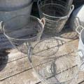 Trois paniers Panier métal grillagé 1950 avec poignées sont posés sur une terrasse en bois en plein soleil, chacun d'entre eux présentant un charme français vintage. Brocante 93