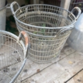 Deux grands paniers Panier métal grillagé 1950 avec poignées reposent sur une surface en bois altérée à l'extérieur, ajoutant un charme rustique vintage. Brocante 93
