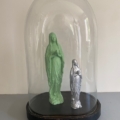 Deux statues de la Vierge Marie, verte et argentée, sont exposées sous le Globe de mariage 1950 - un dôme en verre avec une base noire -, ce qui lui confère un charme vintage. Brocante 93