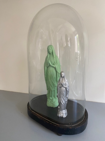 Le Globe de mariage 1950 présente deux statues de la Vierge Marie - l'une verte, l'autre argentée - joliment exposées sous un dôme en verre transparent et posées sur un élégant socle noir. Brocante 93