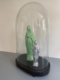 Le Globe de mariage 1950 présente deux statues de la Vierge Marie - l'une verte, l'autre argentée - joliment exposées sous un dôme en verre transparent et posées sur un élégant socle noir. Brocante 93