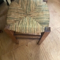Tabouret paille vintage 1960 avec une assise tressée, vue de dessus sur un sol en bois clair. Brocante 93