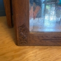 Gros plan sur un Miroir trumeau 1940, avec des sculptures florales sur son cadre en bois, une main réfléchie et un verre à miroir vieilli et trouble. Brocante 93