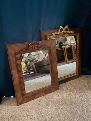 Deux pièces de Miroir noeud PM 1940, chacune ornée d'un nœud gracieux, s'appuient sur un rideau bleu foncé et reflètent un salon confortable. Brocante 93