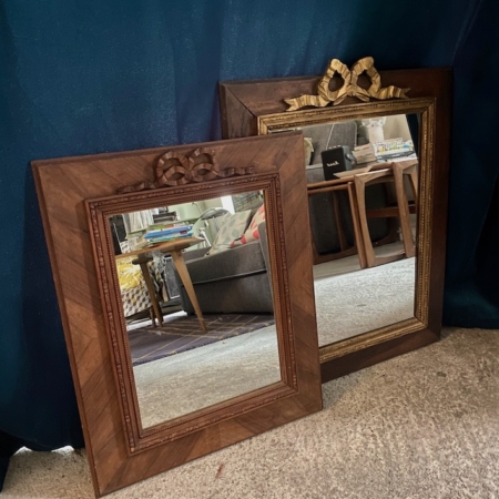Deux pièces de Miroir noeud PM 1940, chacune ornée d'un nœud gracieux, s'appuient sur un rideau bleu foncé et reflètent un salon confortable. Brocante 93