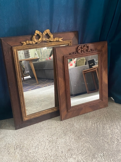 Deux miroirs en bois Miroir noeud PM 1940 ornés de nœuds délicats reposent sur un sol moquetté devant un rideau bleu et un canapé gris, rayonnant d'une élégance raffinée. Brocante 93