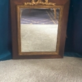Le Miroir noeud PM 1940 présente un design rectangulaire avec un nœud doré sur le dessus, sur un fond bleu foncé et un sol beige. Brocante 93