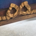 Gros plan d'un ruban doré ornant le cadre en bois du Miroir noeud PM 1940 sur un fond bleu texturé. Brocante 93