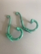 Deux crochets en métal vert et orné - Paire de patères 1930 - au design vintage reposent sur une surface gris clair. Brocante 93