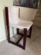 La Chaise Gautier 1970, avec son assise blanche incurvée et son cadre en bois foncé, se trouve près de l'escalier et d'un mur orné d'œuvres d'art. Brocante 93