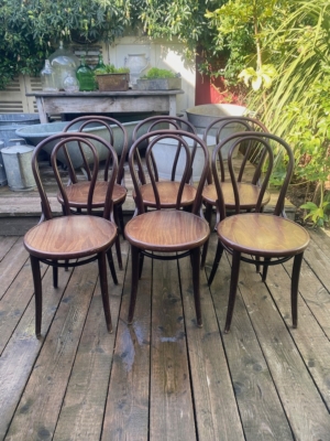 Un bistrot Lot de chaises est aménagé sur une terrasse en bois à l'extérieur, avec six chaises en bois à dossier incurvé entourées de plantes et de décorations de jardin. Brocante 93