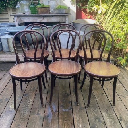 Un bistrot Lot de chaises est aménagé sur une terrasse en bois à l'extérieur, avec six chaises en bois à dossier incurvé entourées de plantes et de décorations de jardin. Brocante 93