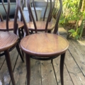 Quatre Lot de chaises bistrot en bois à dossier incurvé sont posés sur une terrasse en bois entourée de verdure - un ensemble accueillant idéal pour se détendre en plein air. Brocante 93