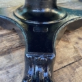 Pied de table en métal noir avec un design de pied en griffe orné sur un plancher en bois usé par les intempéries, évoquant la Table basse début XXème siècle. Brocante 93