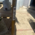 Gros plan sur une tige métallique étiquetée "Lot Utima Made in France" provenant d'une Table pliante Lafuma de 1970, scintillant en plein air à la lumière du soleil. Brocante 93