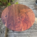 Le Guéridon de bistrot 1950, avec son plateau rond en bois et son grain riche, est posé sur une terrasse usée par le temps et entourée de plantes vertes. Brocante 93